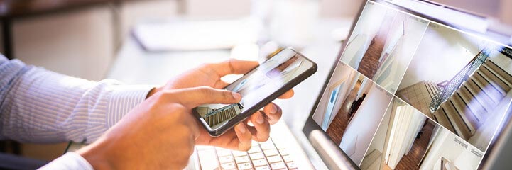 Person using phone and laptop to view home security remotely